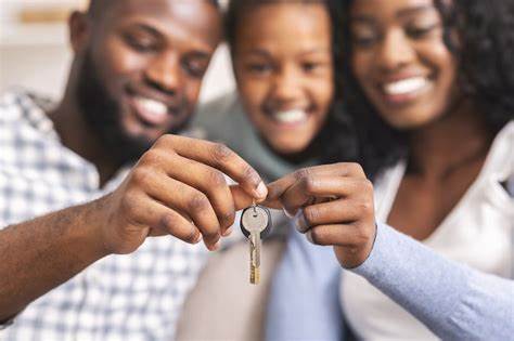 A black man, woman, and child in the middle. The man and woman are holding onto a key and smiling.